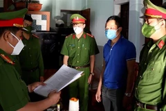 Công an đọc quyết định bắt giữ đối tượng Cao Tiến Dũng. (Ảnh: TTXVN phát)