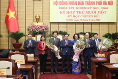 Bí thư Thành ủy Hà Nội Đinh Tiến Dũng tặng hoa chúc mừng bà Vũ Thu Hà (áo dài xanh) được bầu làm Phó Chủ tịch Ủy ban Nhân dân thành phố Hà Nội. (Ảnh: PV/Vietnam+)