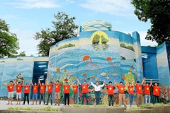 Họa sỹ Nguyễn Thu Thủy cùng các cộng sự thực hiện tác phẩm gắn gốm nghệ thuật Nhà Gương. (Ảnh: Đinh Thuận/TTXVN)