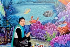 Họa sỹ Nguyễn Thu Thủy bên tác phẩm gắn gốm nghệ thuật Nhà Gương. (Ảnh: Đinh Thuận/TTXVN)