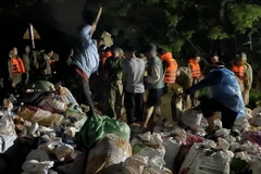 Hàng trăm người dân và các lực lượng chức năng vẫn đang khẩn trương chuyển các bao đất tới vị trí vỡ đê. (Ảnh: Quang Cường/TTXVN)