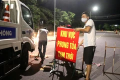 Lực lượng chức năng tháo gỡ biển hiệu phong tỏa Tổ 5A, Khu phố 1, phường Đông Lễ. (Ảnh: Nguyên Lý/TTXVN) 