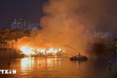 Cảnh sát Phòng cháy chữa cháy sử dụng ca nô chuyên dụng để phun nước vào đám cháy. (Ảnh: TTXVN)
