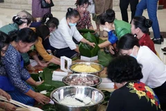 Cựu lưu học sinh Lào tham gia gói bánh chưng. (Ảnh: Phạm Kiên/TTXVN) 