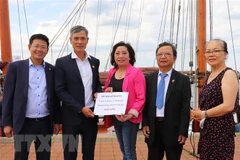 Đại sứ Việt Nam tại Đức, ông Nguyễn Minh Vũ (thứ 2 từ trái sang) tiếp nhận số tiền quyên góp của cộng đồng người Việt ở thành phố Rostock và vùng phụ cận. (Ảnh: Mạnh Hùng/TTXVN) 