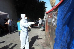 Nhân viên y tế phun thuốc khử trùng nhằm ngăn chặn sự lây lan của dịch COVID-19 tại Baghdad, Iraq. (Ảnh: THX/TTXVN) 