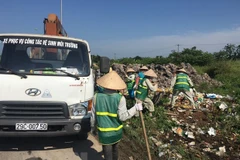 Công nhân Công ty Một thành viên Môi trường đô thị Hà Nội thu dọn rác thải bị đổ trộm tại Đại lộ Thăng Long. (Ảnh: Mạnh Khánh/TTXVN) 
