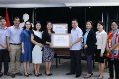 Bà Trịnh Thị Tâm, Công sứ Đại sứ quán Việt Nam tại Lào đang trao tượng trưng cho Chủ tịch Hội người Việt Nam thủ đô Vientiane, ông Nguyễn Văn Mùi, một thùng khẩu trang Chính phủ gửi cho bà con cộng đồng. (Ảnh: Phạm Kiên/Vietnam+) 