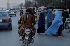 Một nhóm phụ nữ băng qua đường khi các thành viên của Taliban lái xe qua Kabul, Afghanistan. (Nguồn: Reuters) 