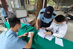 Nhân viên bảo vệ và nhân viên y tế làm nhiệm vụ tại cổng kiểm soát dịch bệnh. (Ảnh: Nam Sương/TTXVN) 