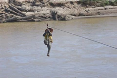 Người dân liều mình đu dây qua sông Pô Kô. (Ảnh: Khoa Chương/TTXVN) 