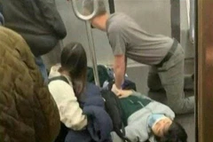 Hành khách sơ cứu cho một người bị thương sau vụ nổ súng trên tàu điện ngầm ở New York, Mỹ ngày 12/4/2022. (Ảnh: AFP/TTXVN)