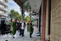 Ông Lê Văn Dẽ (áo trắng) được đưa về nhà để thực hiện lệnh khám xét tại nơi ở. (Nguồn: Báo Khánh Hòa) 