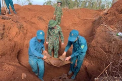 Cơ quan chức năng và cựu chiến binh tiến hành quy tập mộ liệt sỹ. (Nguồn: TTXVN phát) 