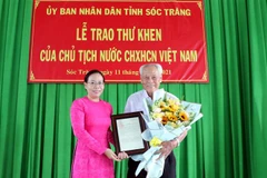 Phó Chủ tịch Ủy ban Nhân dân tỉnh Sóc Trăng Huỳnh Thị Diễm Ngọc trao thư khen của Chủ tịch nước cho ông Trần Cang. (Ảnh: Trung Hiếu/TTXVN) 