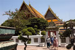 Khách du lịch đeo khẩu trang phòng lây nhiễm COVID-19 khi tham quan một ngôi chùa ở Bangkok, Thái Lan. (Ảnh: AFP/TTXVN) 