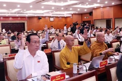 Các đại biểu Hội đồng Nhân dân Thành phố biểu quyết thông qua Nghị quyết tại Kỳ họp. (Ảnh: Xuân Khu/TTXVN)