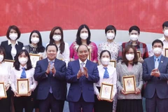 Chủ tịch nước Nguyễn Xuân Phúc tặng ảnh chân dung Chủ tịch Hồ Chí Minh cho các cá nhân có thành tích xuất sắc của Tập đoàn Dệt may Việt Nam. (Ảnh: Thống Nhất/TTXVN) 