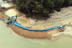 Lực lượng cứu hộ dùng bạt che phủ bên ngoài nhằm gia cố vững chắc thân đập của dòng chảy mới. (Ảnh: Đỗ Trưởng/TTXVN) 