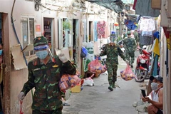 Cán bộ, chiến sỹ Trung đoàn 31, Sư đoàn 309 (Quân đoàn 4) chuyển quà cho nhân dân vùng dịch ở phường 16, Quận 8, TP Hồ Chí Minh. (Ảnh: Thanh Vũ/TTXVN) 