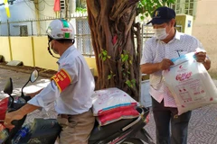 Đảng viên chi bộ khu dân cư Xuân Đán 5 tham gia Ban điều hành dân phố vận chuyển gạo đi phát cho hộ dân trong khu dân cư. (Ảnh: Trần Lê Lâm/TTXVN) 