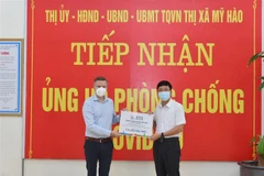 Ông Urs Kloeti, Giám đốc nhà máy Nestlé Bông Sen tại Hưng Yên, trao quà cho lãnh đạo thị xã Mỹ Hào để tiếp sức cho người dân bị ảnh hưởng bởi dịch COVID-19. (Ảnh: Đinh Tuấn/TTXVN) 