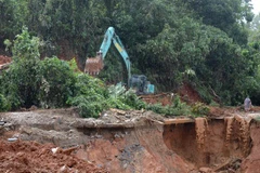 Xe múc, xe ủi đang tích cực dọn dẹp khu vực sạt lở. (Ảnh: Quốc Dũng/TTXVN) 