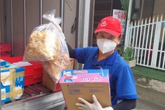 Nhà báo Phạm Đỗ Minh Trung mang hàng hóa đến các khu dân cư, khu vực cách ly tập trung. (Ảnh: Ngọc Thiện/TTXVN) 