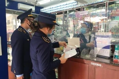 Cục Quản lý thị trường Quảng Ninh kiểm tra hoạt động kinh doanh kit test nhanh và thuốc điều trị COVID-19 tại một cơ sở bán thuốc. (Ảnh: TTXVN phát) 