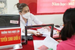 Ban tuyển sinh trường THCS Ngọc Lâm, quận Long Biên, Hà Nội hỗ trợ phụ huynh kiểm tra hồ sơ, giải đáp thắc mắc trong cách thức tuyển sinh trực tuyến cho con em vào lớp 6. (Ảnh: Thanh Tùng/TTXVN) 