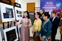 Bà Trần Thị Thu Đông, Phó Chủ tịch Liên hiệp các hội Văn hóa Nghệ thuật Việt Nam, Chủ tịch Hội Nghệ sĩ Nhiếp ảnh Việt Nam giới thiệu các bức ảnh với khách tham quan Triển lãm. (Ảnh: Phạm Kiên/TTXVN)