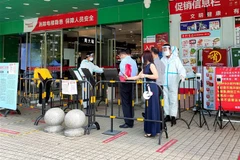 Người dân xếp hàng để kiểm tra thông tin trước khi vào siêu thị tại Thâm Quyến, Trung Quốc. (Ảnh: AFP/TTXVN) 