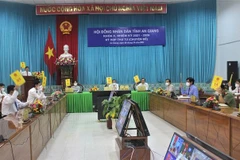 Các đại biểu tham dự kỳ họp tại điểm cầu Văn phòng Ủy ban Nhân dân tỉnh biểu quyết thông qua các nghị quyết. (Ảnh: Thanh Sang/TTXVN) 