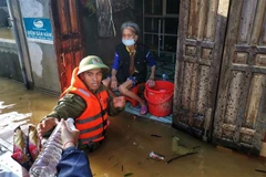 Lực lượng công an huyện Lệ Thủy lội nước, đưa hàng cứu trợ đến những gia đình bị cô lập trong nước lũ. (Ảnh: Thành Đạt/TTXVN) 