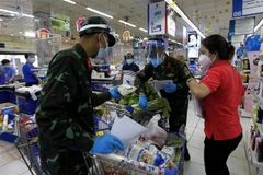 Nhiều chiến sỹ nhờ trợ giúp thông tin, hàng hóa từ các nhân viên siêu thị để đi chợ giúp dân đúng và đầy đủ theo nhu cầu. (Ảnh: Thanh Vũ/TTXVN) 