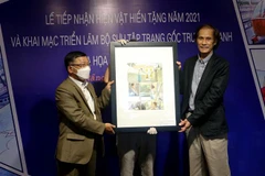 Đại diện họa sỹ Vĩnh Khoa (bên phải) trao tặng hiện vật tranh cho Bảo tàng Mỹ thuật Đà Nẵng tại buổi lễ. (Ảnh: Trần Lê Lâm/TTXVN) 