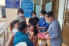 Các hội, đoàn thể của huyện và xã Tân Hòa sửa soạn cho bé L.Y.D trước khi bé về quê cùng cha ruột. (Ảnh: Đậu Tất Thành/TTXVN) 