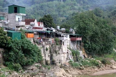 Những ngôi nhà dựng đứng bên bờ sông của một số hộ dân thị trấn Mường Xén, huyện Kỳ Sơn (Nghệ An) tiềm ẩn nguy cơ sạt lở bất cứ lức nào. (Ảnh: Văn Tý/TTXVN) 