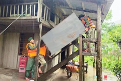 Cán bộ chiến sỹ Đồn Biên phòng Làng Mô, Bộ đội Biên phòng Quảng Bình giúp người dân di dời đồ đạc, tài sản lên chỗ an toàn phòng tránh mưa lũ. (Ảnh: TTXVN phát) 