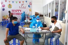 Các công nhân đang làm việc theo phương án "3 tại chỗ" tại Khu chế xuất Tân Thuận, quận 7, Thành phố Hồ Chí Minh kiểm tra y tế trước khi tiêm mũi vaccine thứ 2. (Ảnh: Thanh Vũ/TTXVN) 
