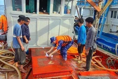 Lực lượng cảnh sát biển niêm phong số dầu không rõ nguồn gốc trên tàu cá. (Ảnh: TTXVN phát)