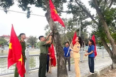 Đoàn viên thanh niên treo cờ Tổ quốc và cờ Đảng xung quanh hồ Mai Trai, xã Vạn Thắng, huyện Ba Vì. (Ảnh: Mạnh Khánh/TTXVN)
