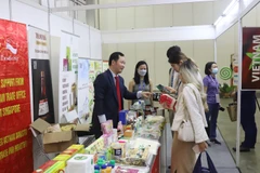 Ông Cao Xuân Thắng, Đại diện Thương vụ Việt Nam tại Singapore, (trái) giới thiệu các sản phẩm chế biến mới của Việt Nam tới các doanh nghiệp quốc tế. (Ảnh: Nguyễn Thúy-Lê Dương/TTXVN)