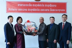 Đại sứ Lê Thị Tuyết Mai, Trưởng Phái đoàn thường trực Việt Nam (áo dài), chúc mừng Phái đoàn thường trực Lào tại Geneva. (Ảnh: Nguyễn Tuấn/TTXVN)