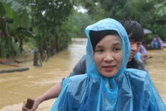 Phóng viên Hạnh Nguyên, báo Đại Đoàn Kết, trong lần tác nghiệp đưa tin về mưa lũ tại huyện Hương Khê, Hà Tĩnh. (Ảnh: Hoàng Ngà/TTXVN) 