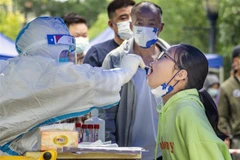 Nhân viên y tế lấy mẫu xét nghiệm COVID-19 cho người dân tại Tứ Xuyên, Trung Quốc. (Ảnh: AFP/TTXVN)