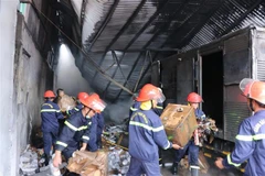 Lực lượng chữa cháy vận chuyển tài sản còn lại ra ngoài. (Ảnh: Tuấn Anh/TTXVN)