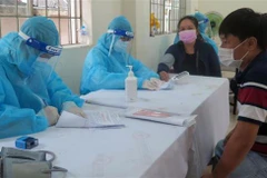 Nhân viên Y tế khám sàng lọc cho người dân trước khi tiêm vaccine COVID-19. (Ảnh: Xuân Triệu/TTXVN) 