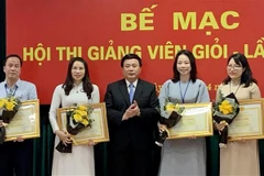 Giáo sư, Tiến sỹ Nguyễn Xuân Thắng, Ủy viên Bộ Chính trị, Chủ tịch Hội đồng Lý luận Trung ương, Giám đốc Học viện, Trưởng ban Chỉ đạo Hội thi trao bằng khen cho 4 giảng viên đạt danh hiệu Giảng viên xuất sắc. (Ảnh: Việt Đức/TTXVN) 