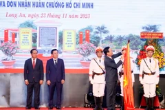 Chủ tịch nước Võ Văn Thưởng gắn Huân chương Hồ Chí Minh lên cờ truyền thống của tỉnh Long An. (Ảnh: Thống Nhất/TTXVN)